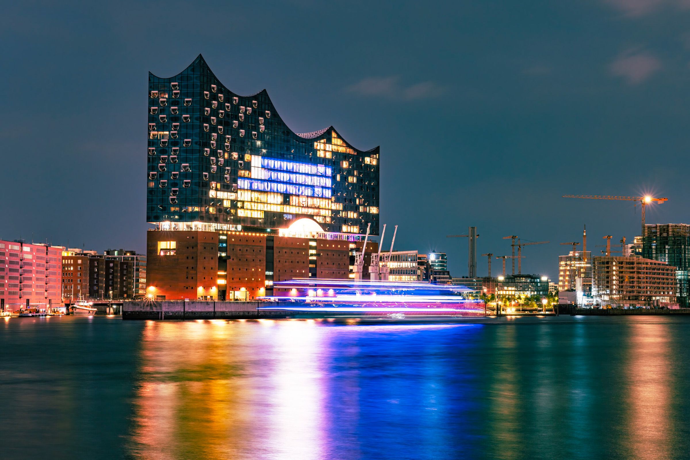 Lichtspuren von Schiffen vor einem Gebäude am Fluß, Langzeitbelichtung